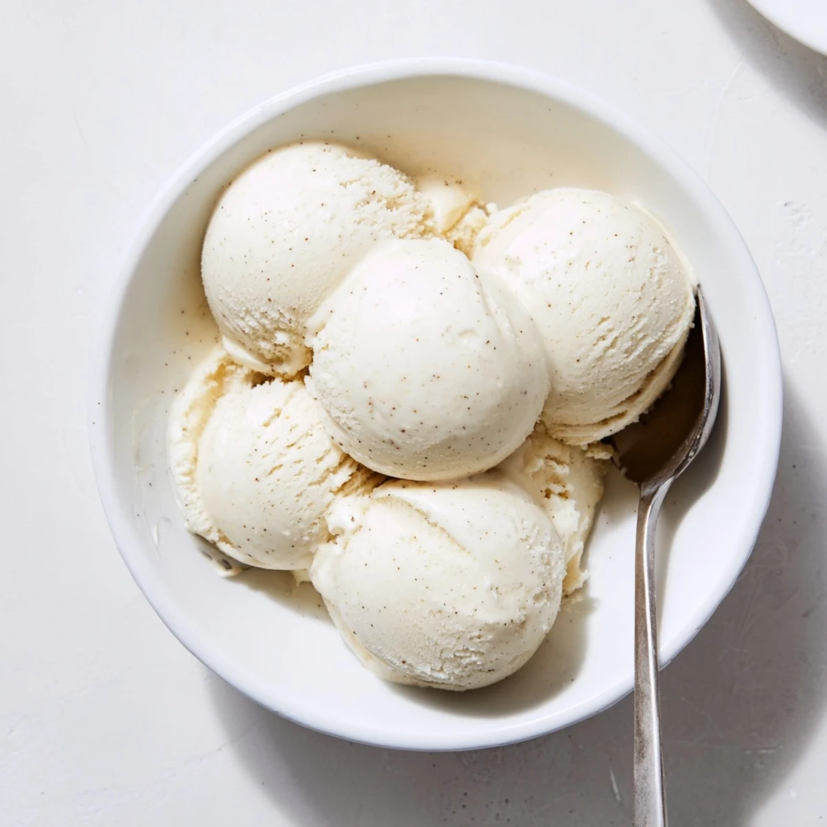 Silky smooth homemade ice cream displaying thick custard texture in a white porcelain serving dish