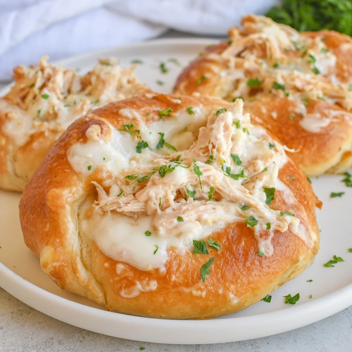Golden baked chicken pillows with crescent dough drizzled with creamy parmesan sauce