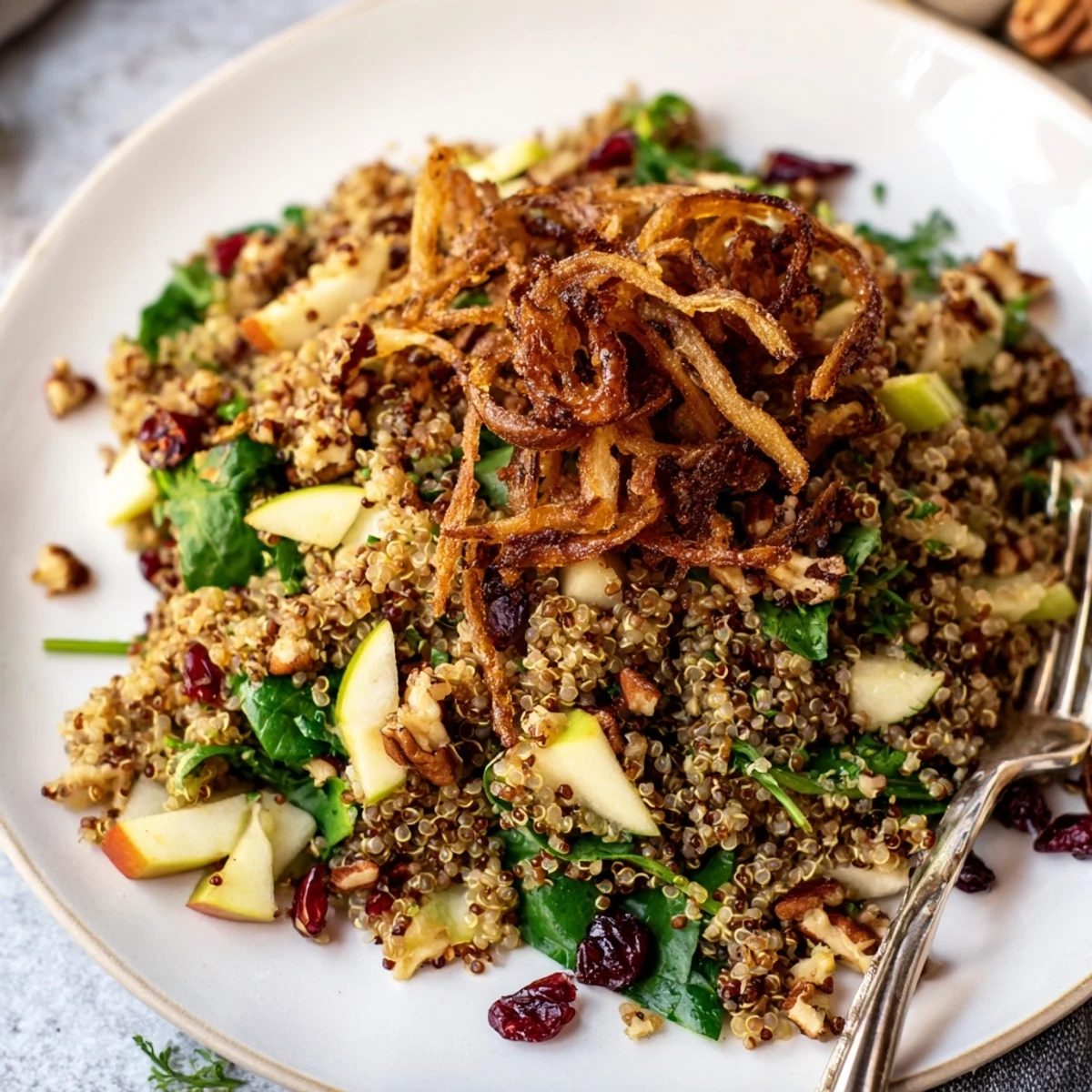 Golden crispy shallots crown a colorful honey mustard quinoa apple salad in a rustic bowl