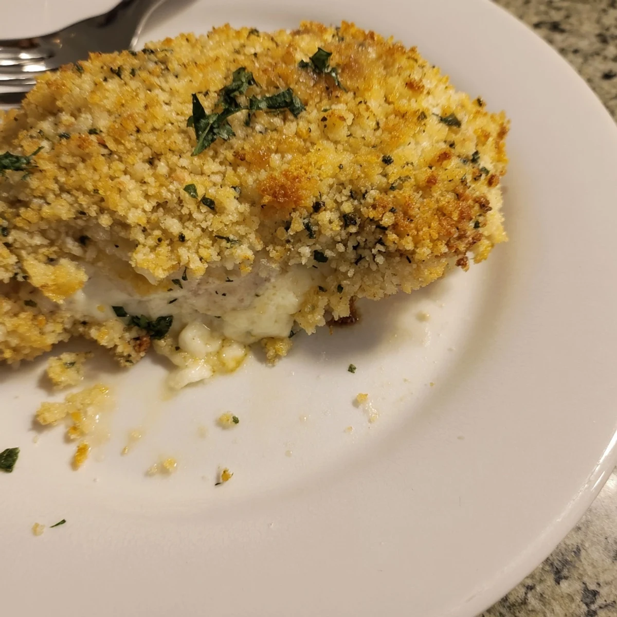 Ricotta chicken bake served steaming on a white plate with fresh parsley garnish