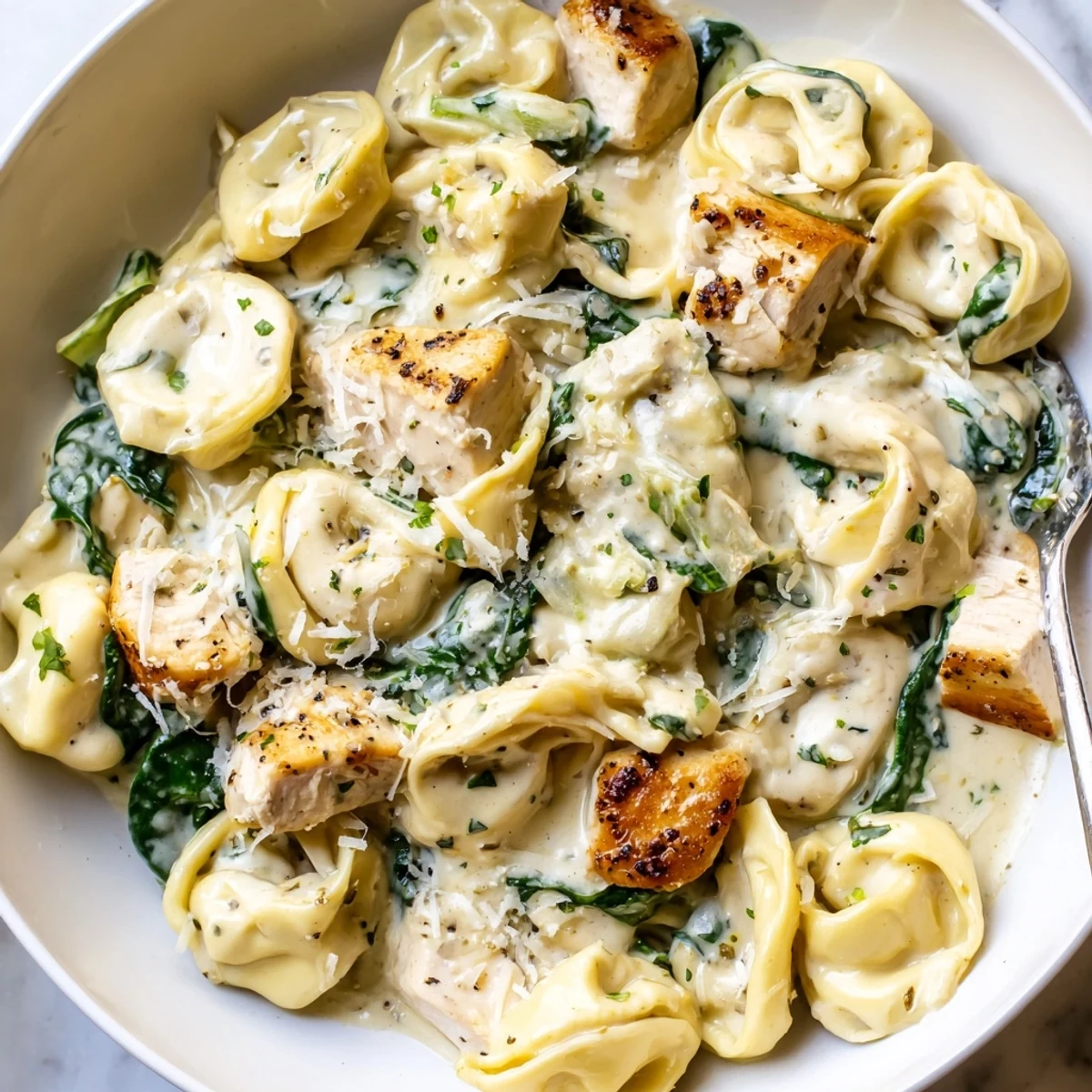 Creamy garlic chicken tortellini with spinach in a velvety white sauce served steaming
