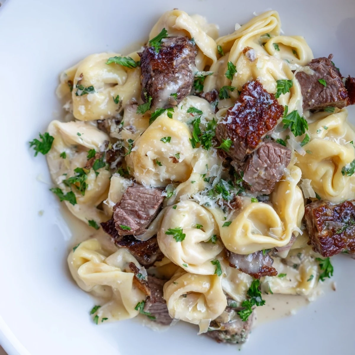 Creamy garlic steak tortellini in a golden Parmesan sauce topped with fresh parsley