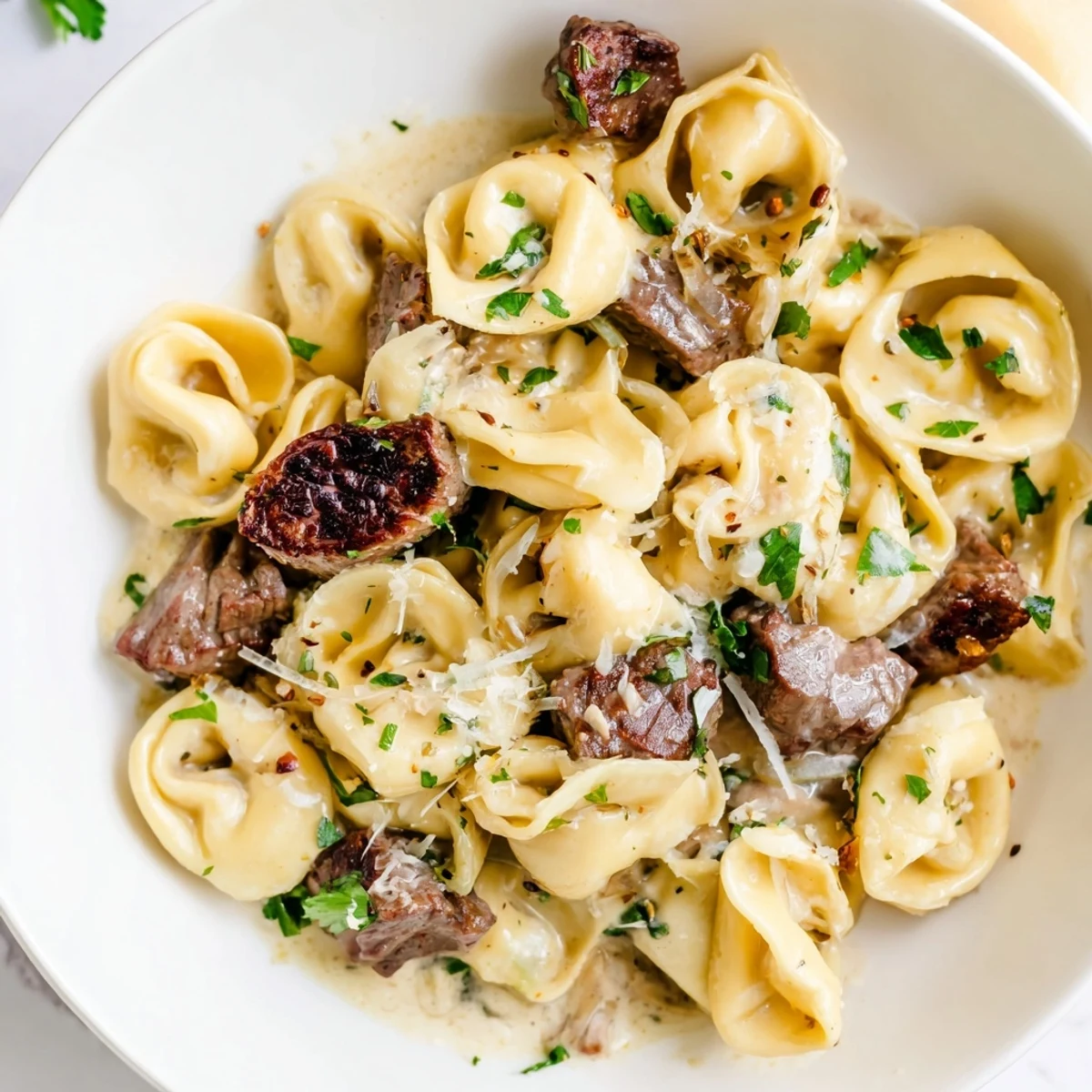 Sizzling steak bites nestled over cheesy tortellini drenched in a silky garlic cream sauce