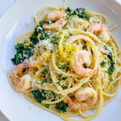 Fork twirling strands of Lemon Garlic Shrimp Pasta with Spinach, with garlic butter sauce clinging to noodles.