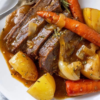 Slow Cooker Pot Roast with Carrots and Potatoes in a ceramic slow cooker, steam rising from the tender beef, carrots, and potatoes.