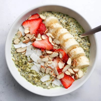 Layered Matcha Protein Overnight Oats showing creamy texture, served with toasted coconut flakes and chopped nuts.