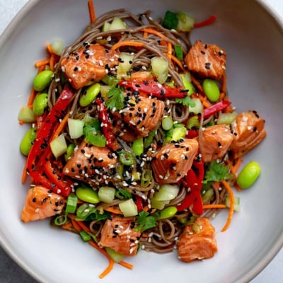 Teriyaki salmon soba noodle salad showcases flaky glazed fish, colorful julienned carrots, and refreshing cucumber slices.