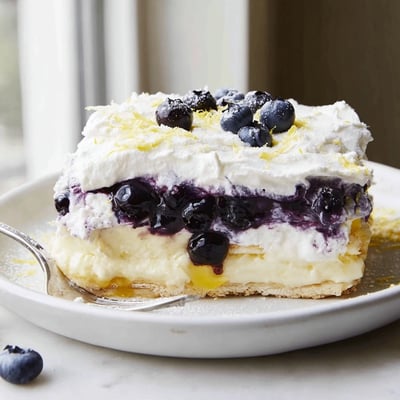 Creamy Lemon Blueberry Lasagna topped with whipped cream, bright lemon zest